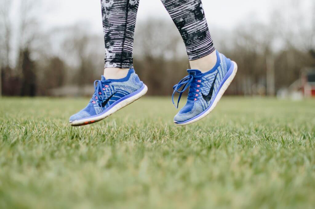 A runner jumping in a grassy field