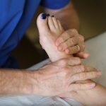 A podiatrist manipulating the foot of a patient with foot pain